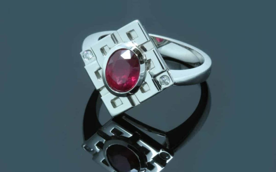 Image of an oval cut Fair Trade ruby set in a recycled platinum engagement ring featuring Buddhist symbols