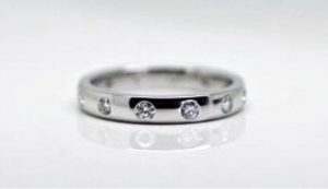 Ring image: Handmade wedding ring. With its polished metal band, this ring features a collection of small white diamonds, hammer set into the band.