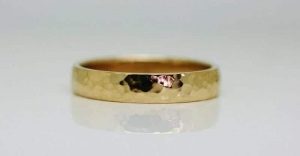 Ring image: Handmade wedding ring. Crafted from recycled 18 carat yellow gold, this simple wedding ring features a beaten texture across the band.