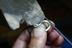 Image of a jeweller hand making a pendant from recycled white gold