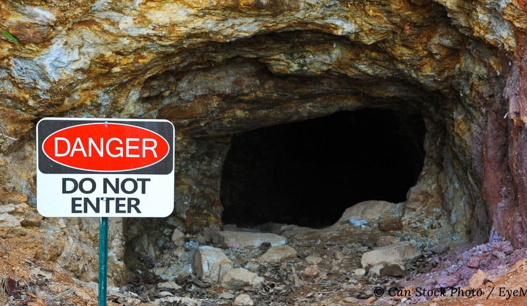 Photo of an abandoned gold mine with a safety warning outside