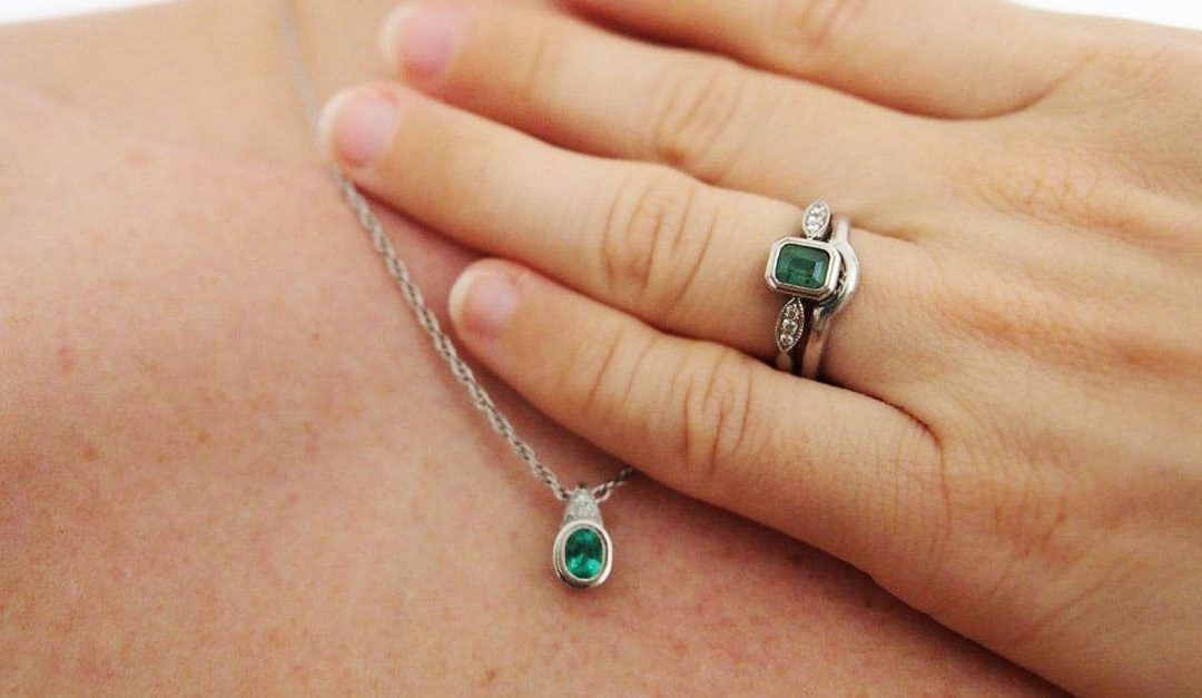 Photo of a matching West Australian emerald engagement ring and pendant and wedding ring all made with recycled precious metals