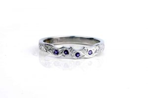 Engraved fitted wedding ring in recycled platinum featuring four Fair Trade amethysts