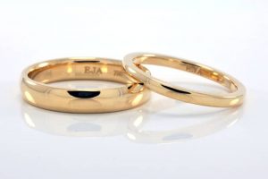 Matching pair of his and hers wedding rings in 18 carat recycled gold in a simple half-round profile with a polished finish.