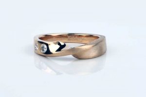 18 carat recycled rose gold wedding ring with a Mobius twist, set with recycled diamonds and finished half polished and half wire-brushed.