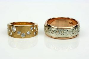 Pair of wedding bands - hers a tapered 18 carat gold band with recycled diamonds in a Gemini constellation patter, and for him (a keen surfer) recycled 18 carat rose gold with a recycled silver sleeve embossed with a bubble pattern 